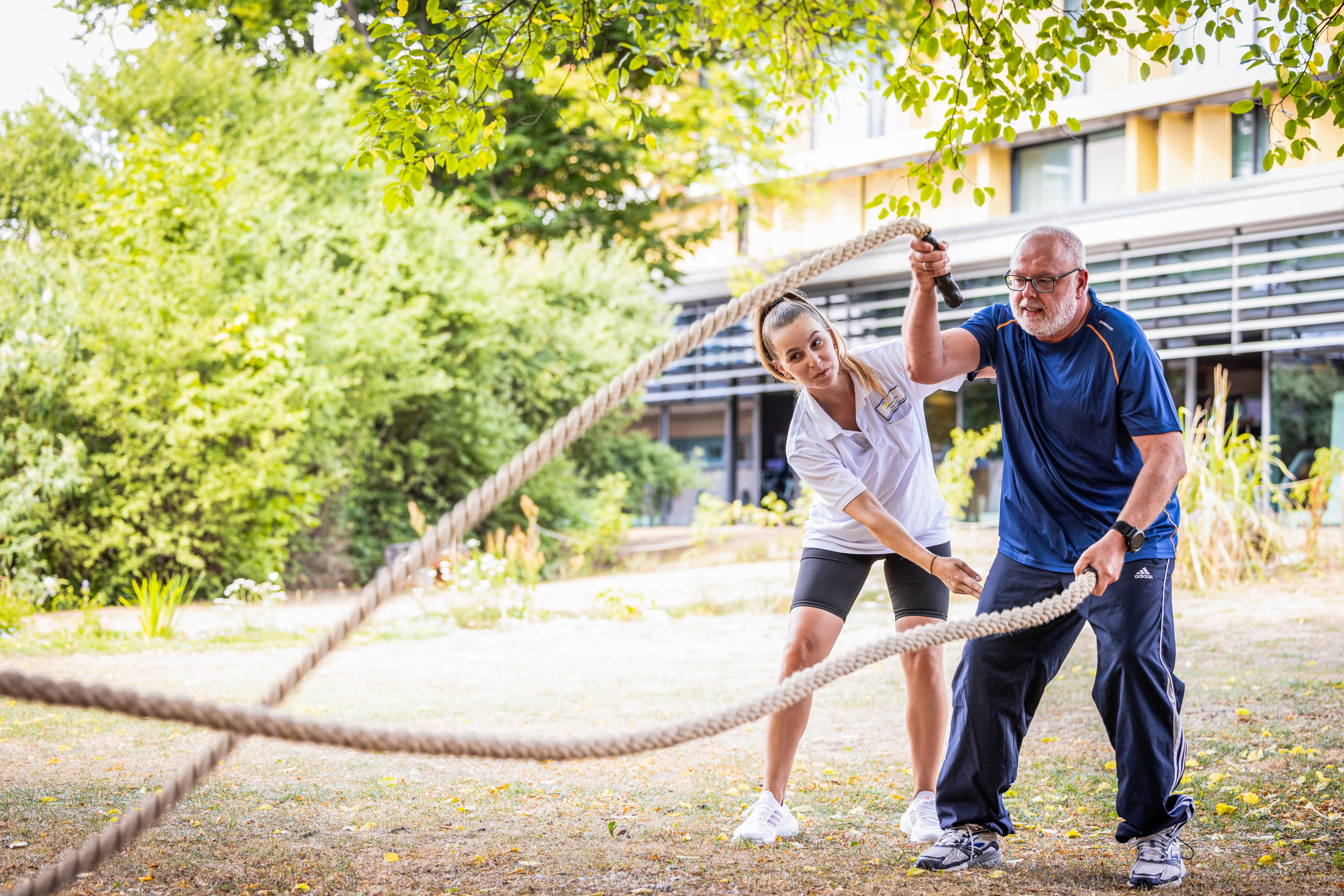 Therapeut mit einem Patienten machen Übungen mit zwei Seilen