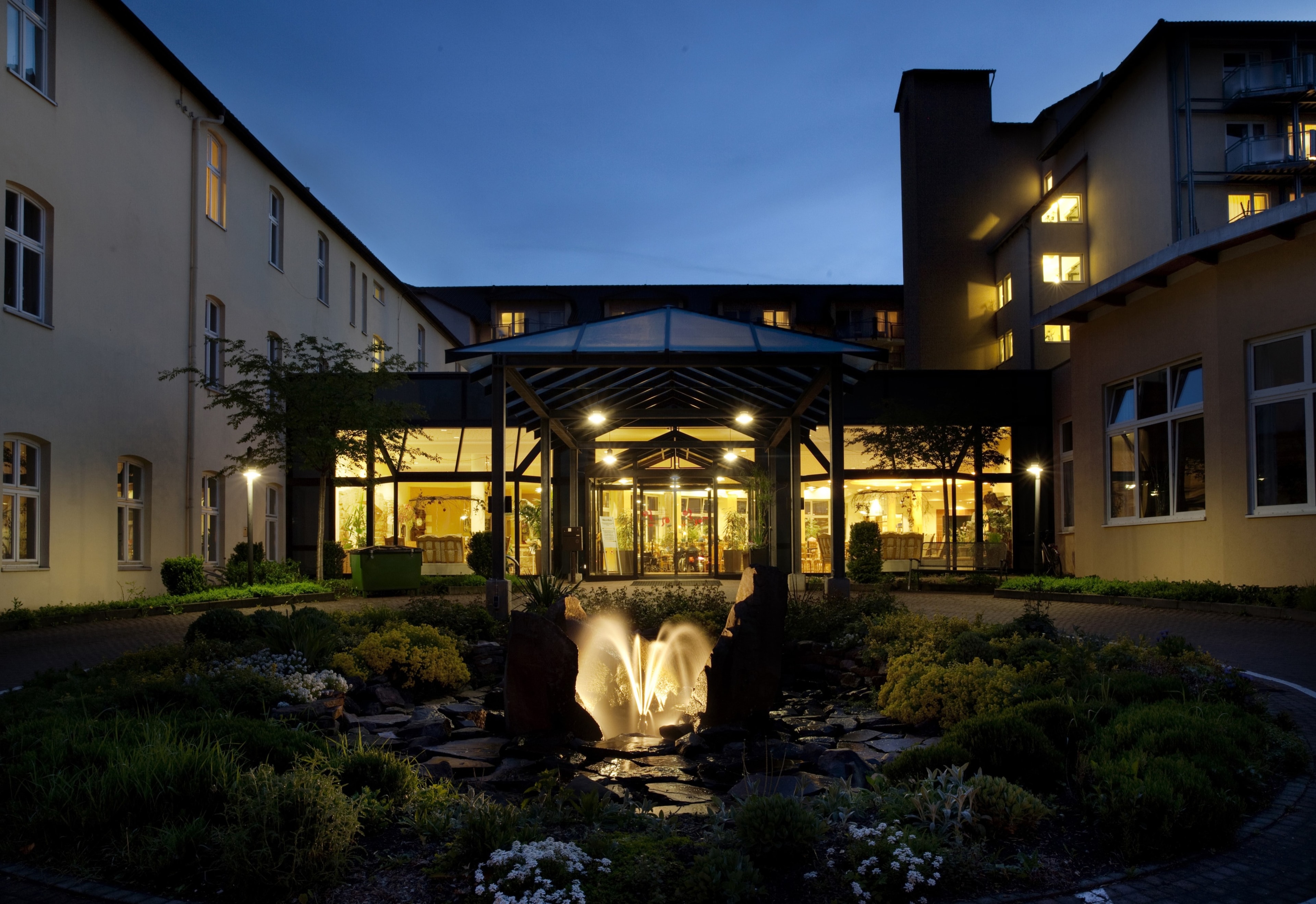 Eingang der BW Kiliani Klinik bei Nacht. Beleuchteter Brunnen im Vordergrund.