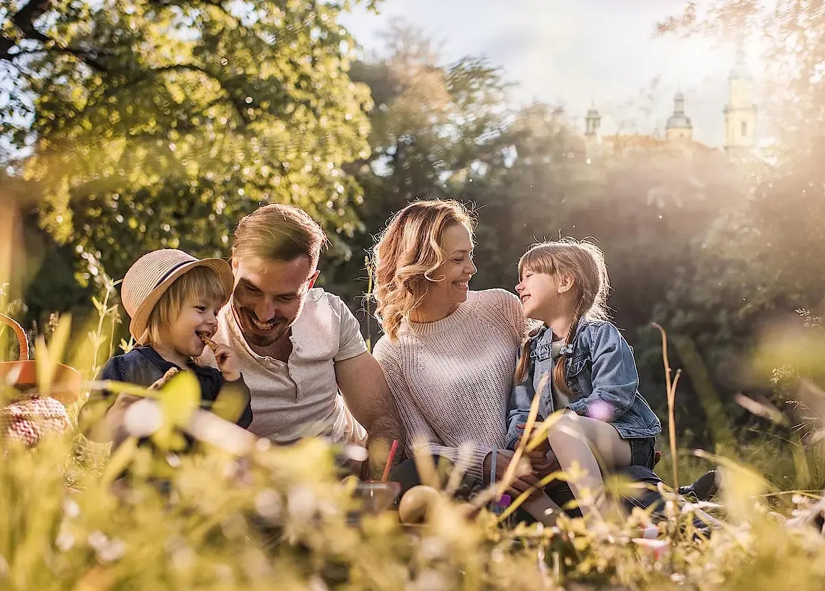 Familie: Mutter, Vater und zwei Kinder sitzen auf dem Rasen in der Natur