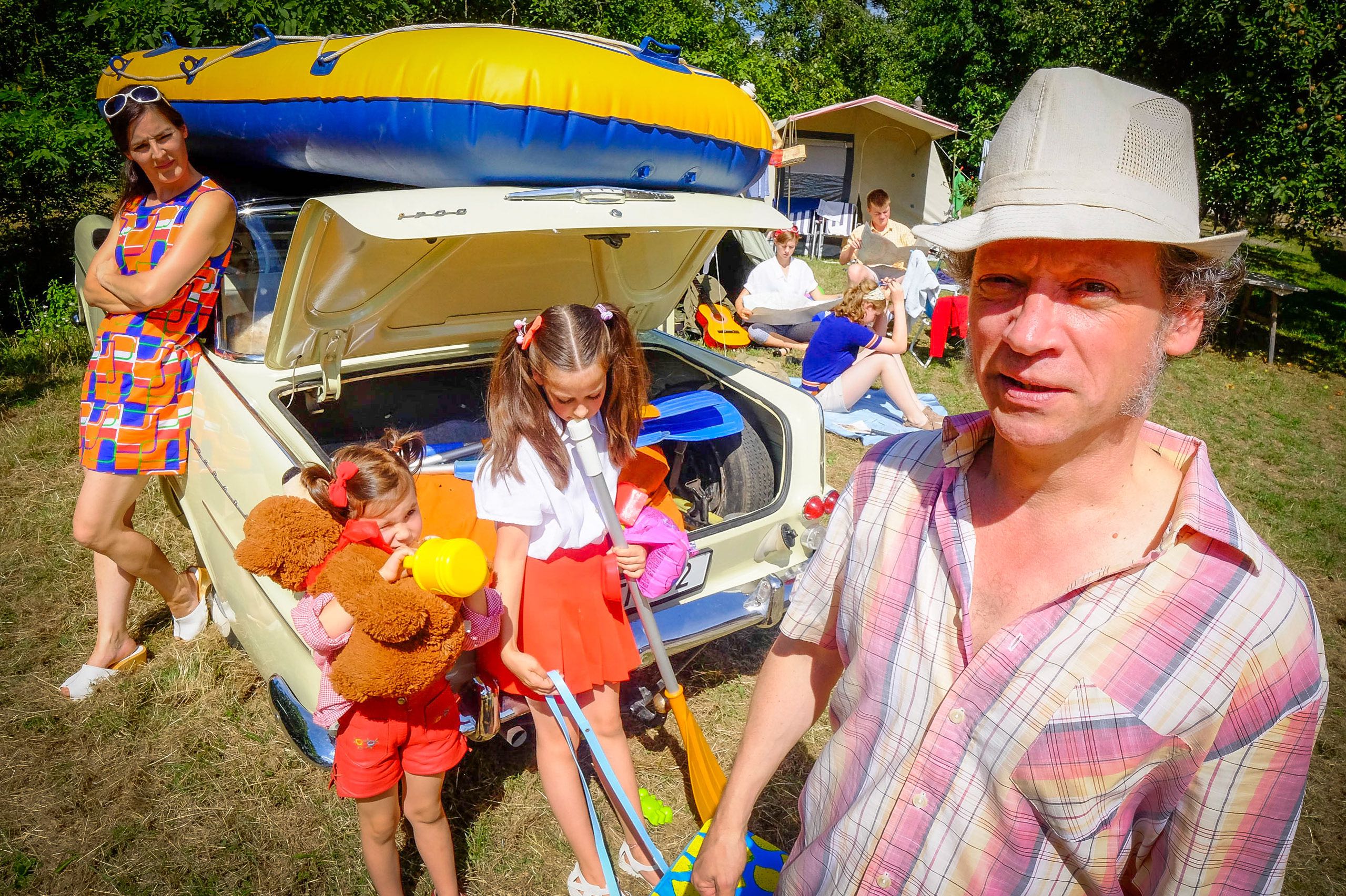 Eine Familie in 70er Jahre Theaterkostümen, Vater, Mutter, 2 Töchter um ein einen Oldtimer herum gruppiert, darauf ein Gummiboot, Bühnenbild ist ein Campingplatz im Fränkischen Freilandmuseum Bad Windsheim, Szenenbild aus dem Stück "Der letzte Sommer" vom Freilandtheater 2017